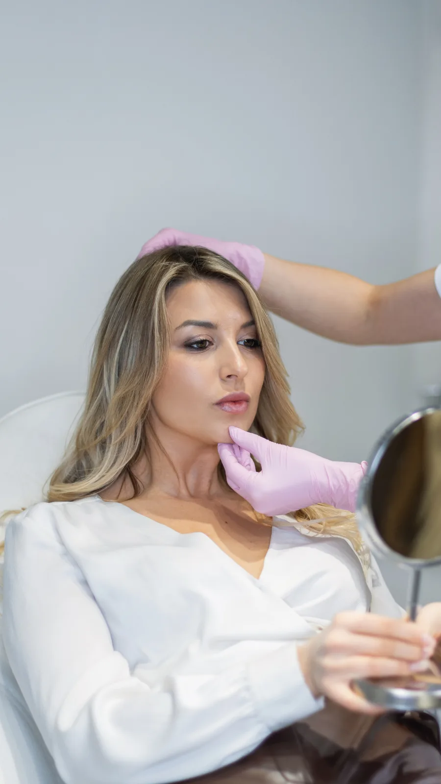 Woman reviewing her results in a mirror with her provider at Advanced Aesthetics