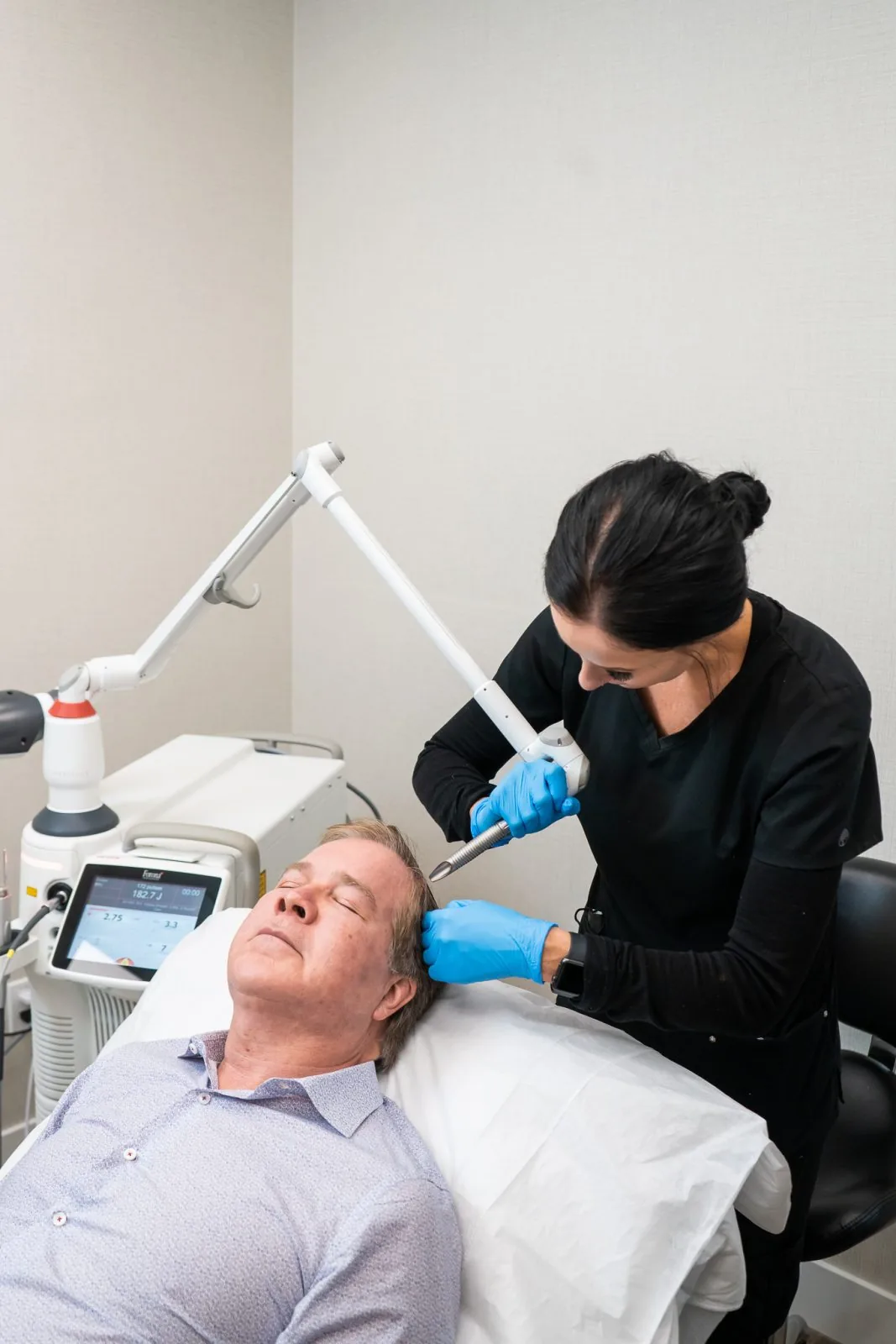 Provider treating a male patient's scalp with the Fotona laser at Advanced Aesthetics